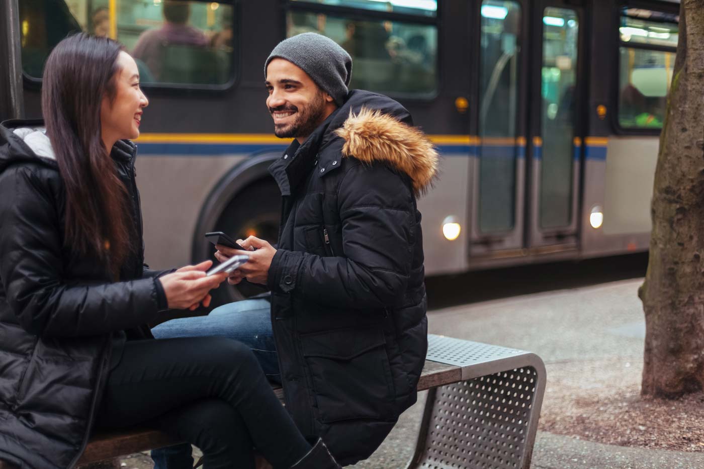Two people smiling at each other with a bus in the background in Vancouver